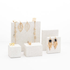 Gold earrings displayed on white stands with a white background