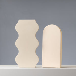 Two beige concrete bookends with wavy design on a gray background